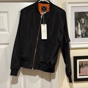 Black windbreaker with orange lining. Never worn. Pockets on sides and on sleeve